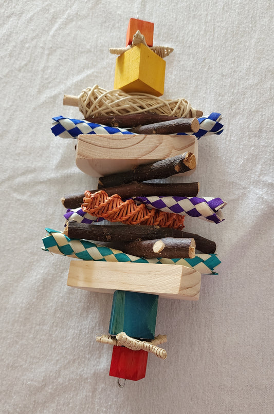 A colorful pet chew toy made of pine wood and bamboo shredders, decorated with a small apple stick and a loofah slice.